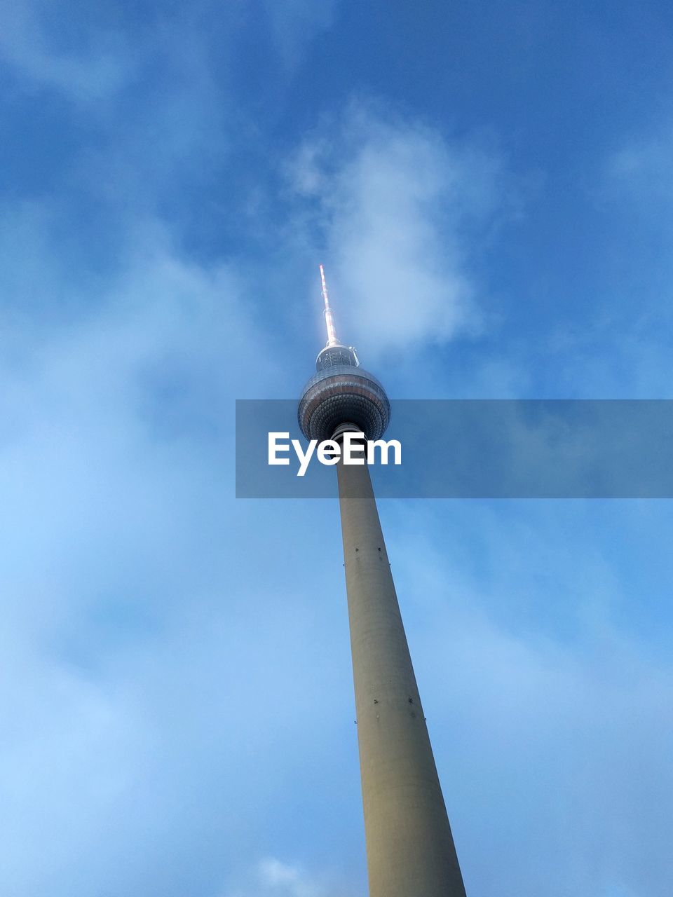 LOW ANGLE VIEW OF COMMUNICATIONS TOWER AGAINST CLOUDY SKY IN CITY