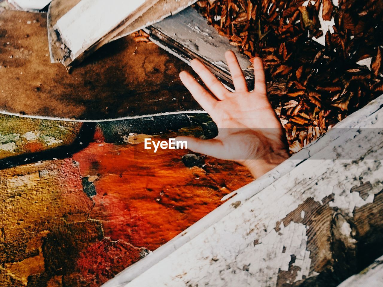 Cropped image of hand against weathered wall