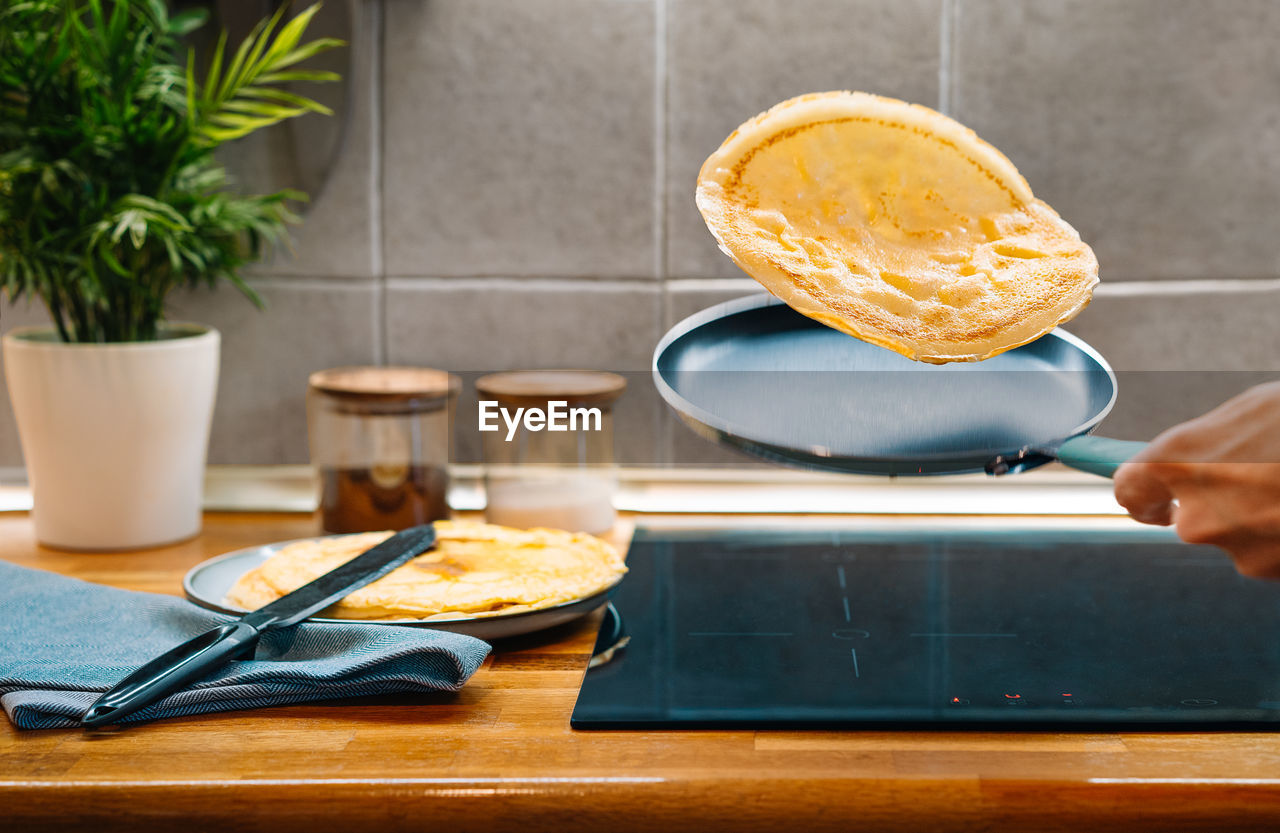 Midsection of person cooking pancakes in pan on kitchen counter
