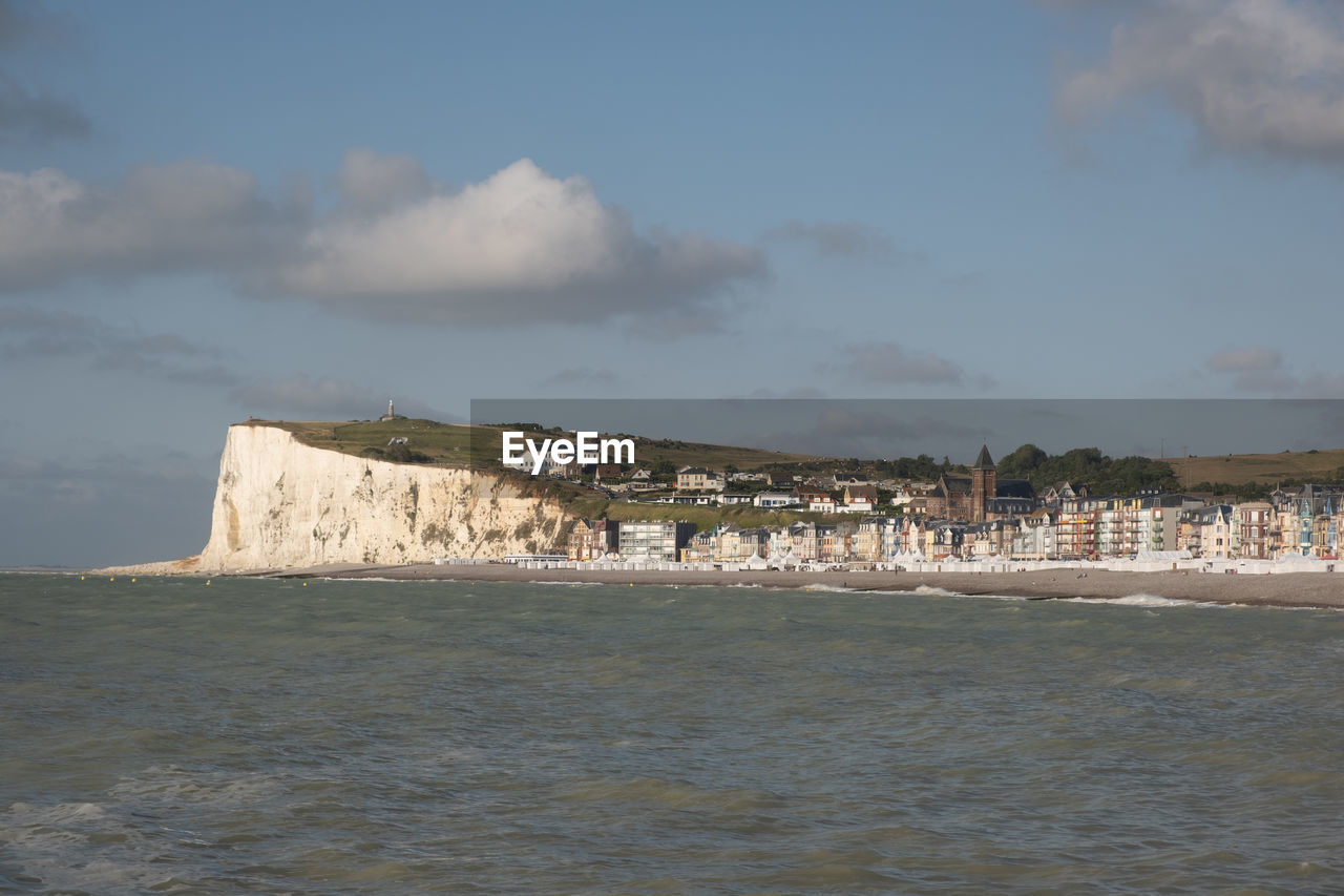 Scenic view of sea by buildings against sky