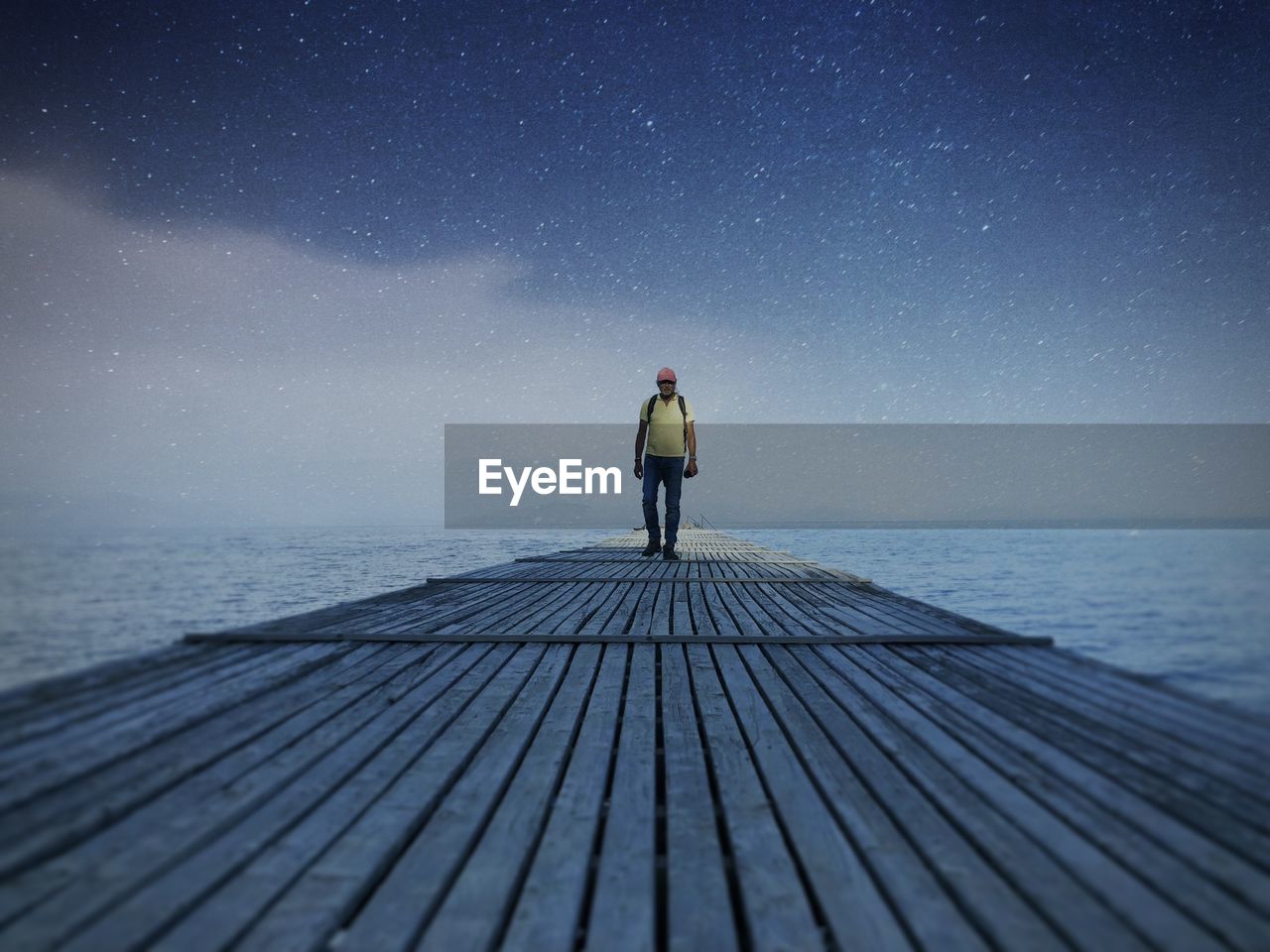 Man standing on pier over against sky at night