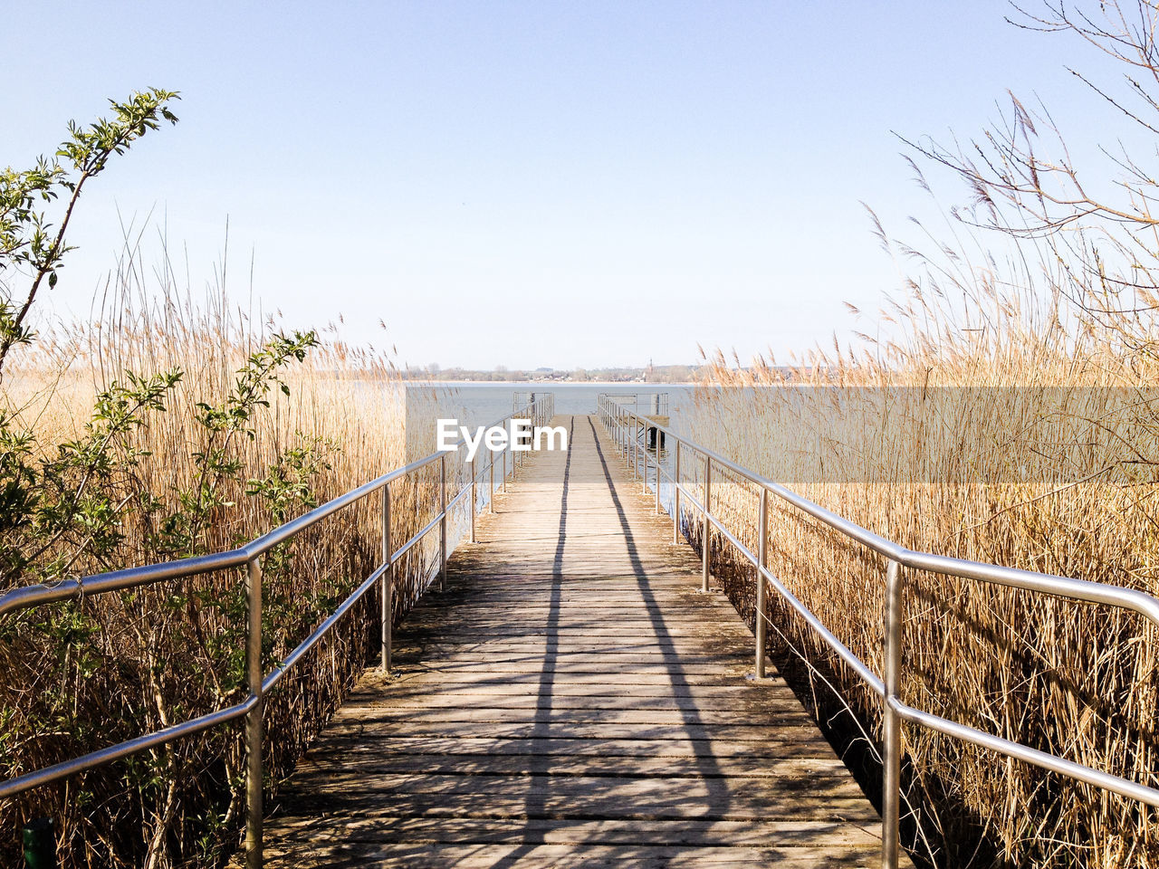 FOOTBRIDGE LEADING TOWARDS SEA AGAINST CLEAR SKY