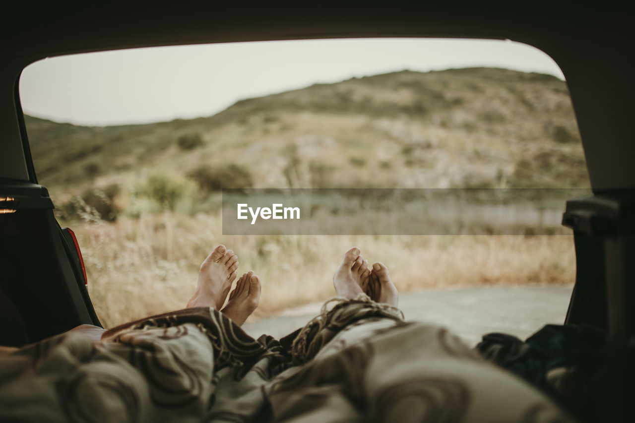 Tired mid adult couple lying in car trunk