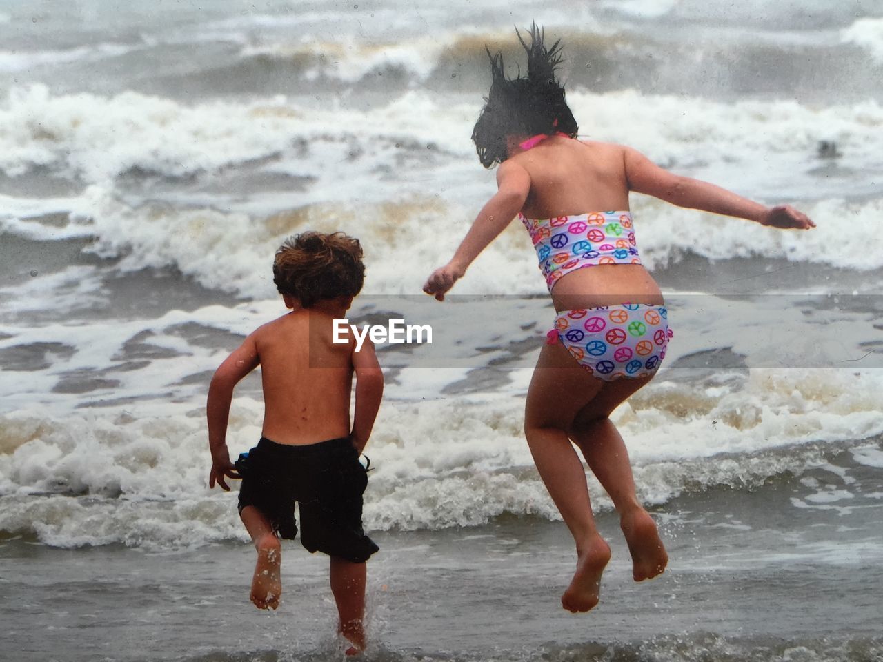 Rear view of sibling enjoying in sea