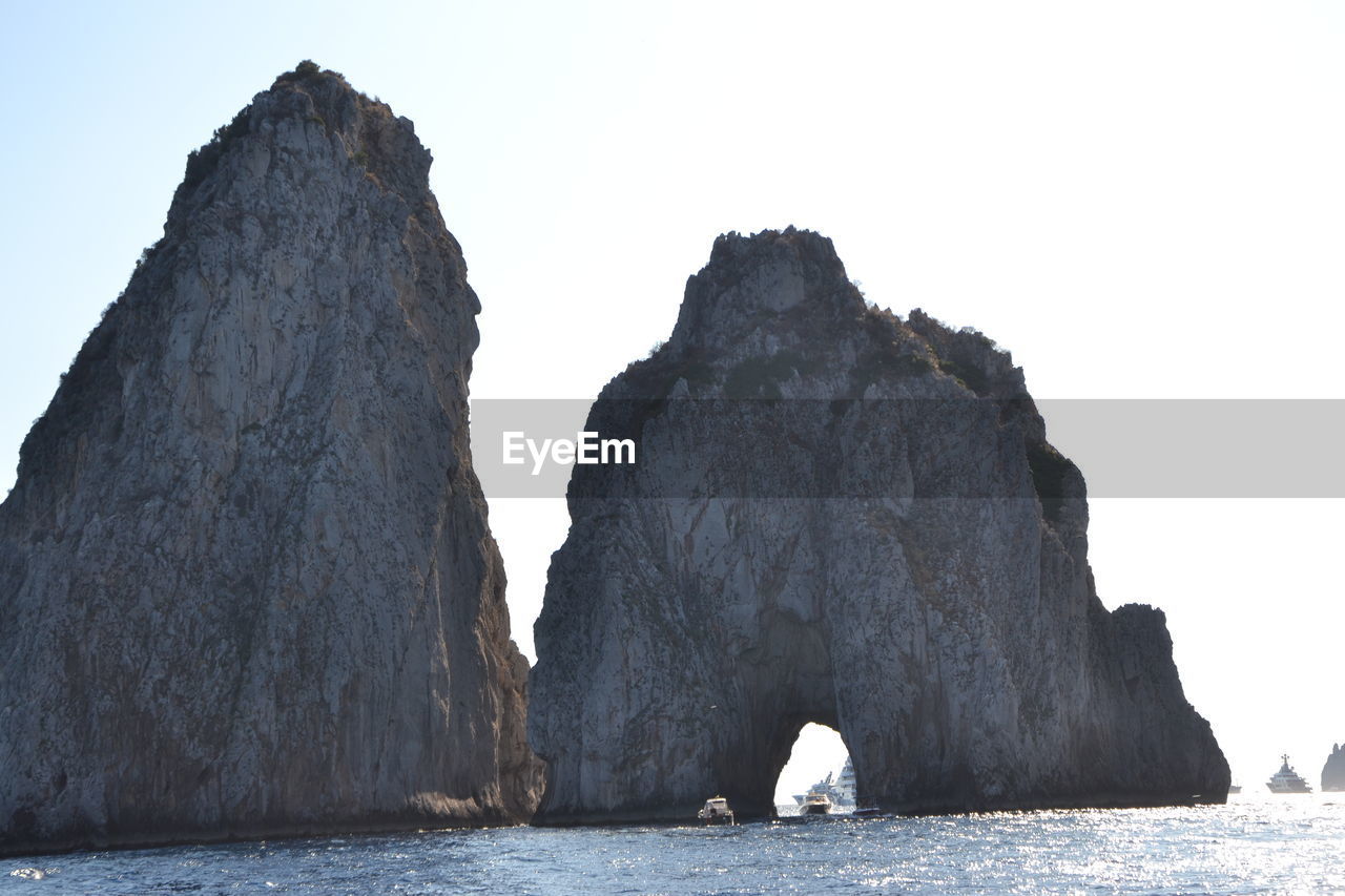 Rock formation by sea against clear sky