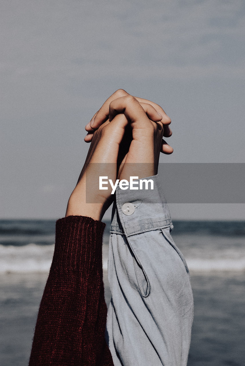 Cropped image of women holding hands at beach