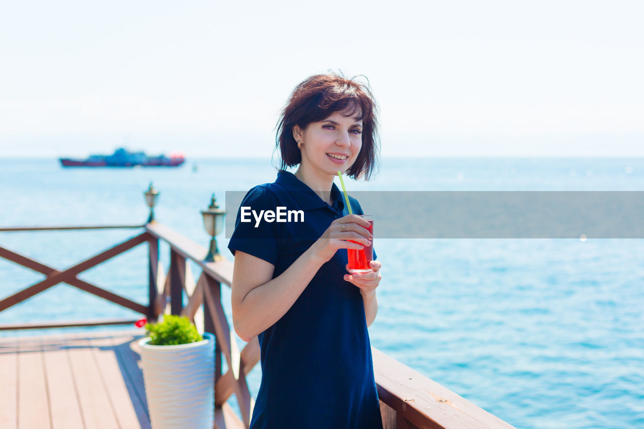 Brunette with a glass of juice in a cafe on the beach.