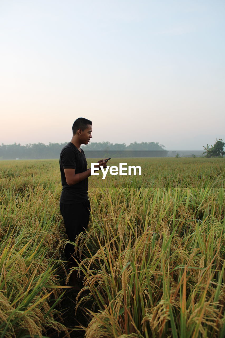 Side view of young man standing on field