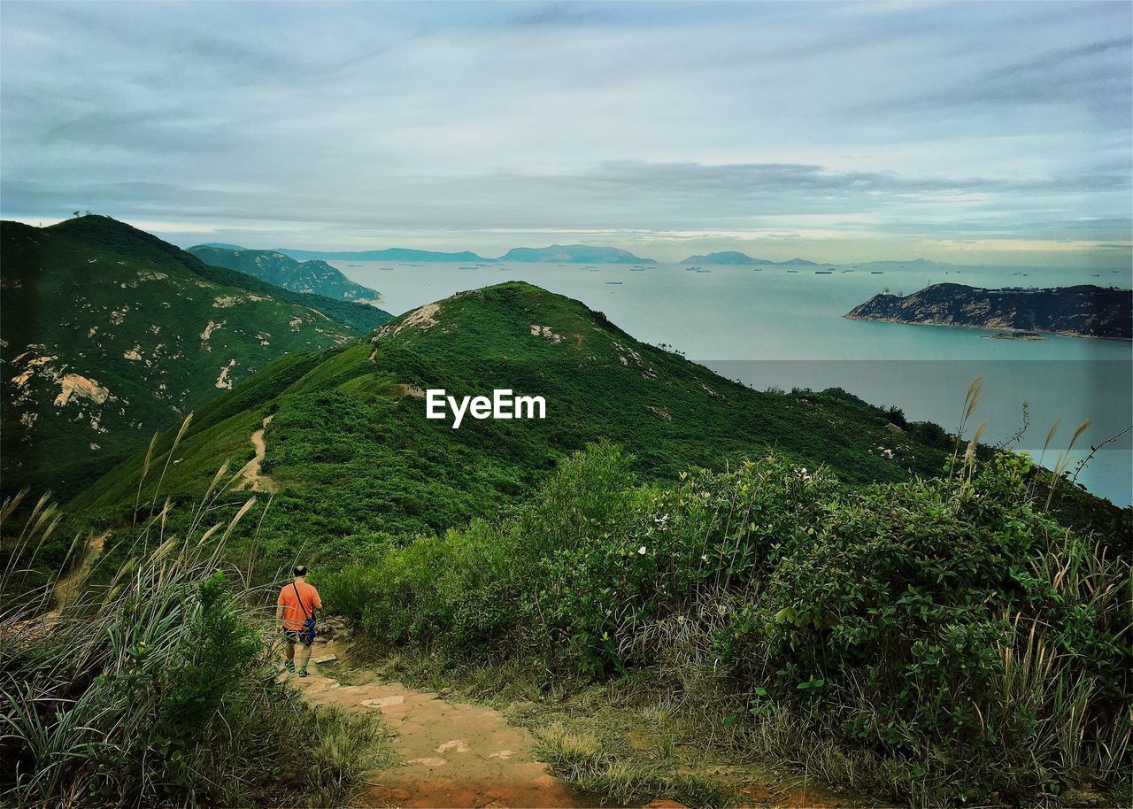 High angle view of man hiking on mountain against sky