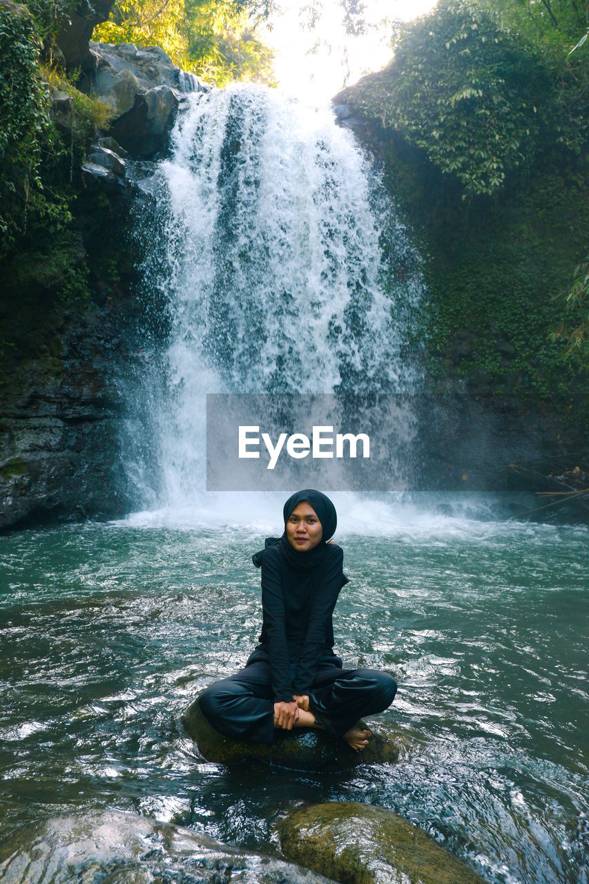 Female tourist playing in the waterfall