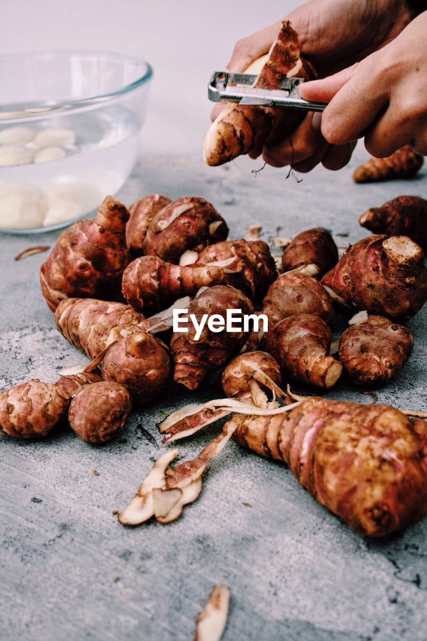 Cropped hands peeling jerusalem artichoke