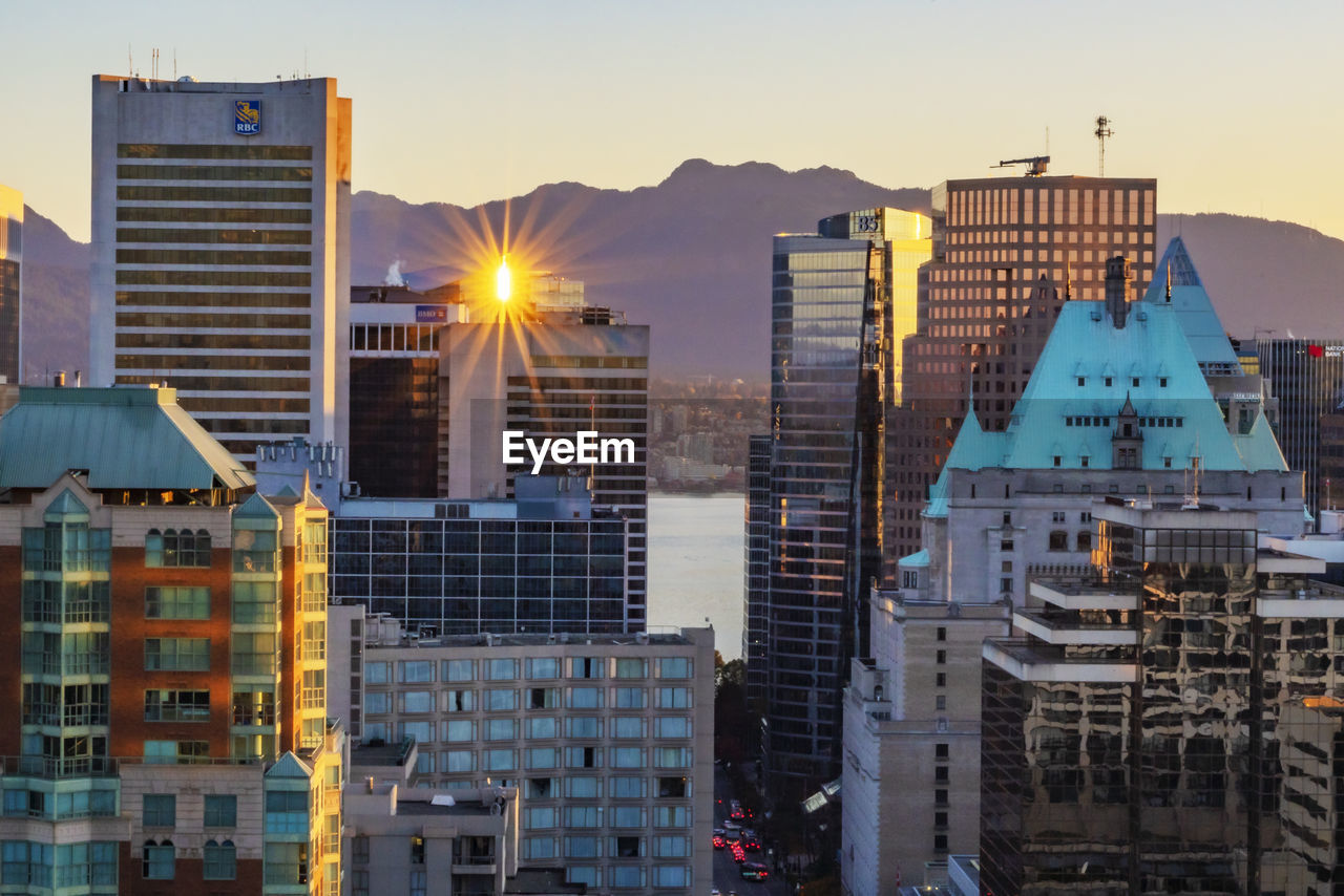 Modern buildings in city against sky during sunset