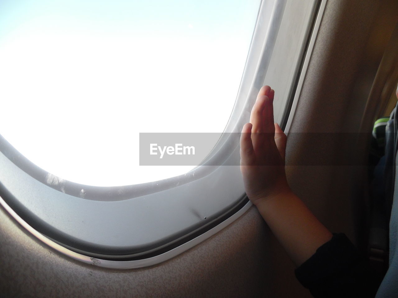 Cropped image of child hand on airplane window