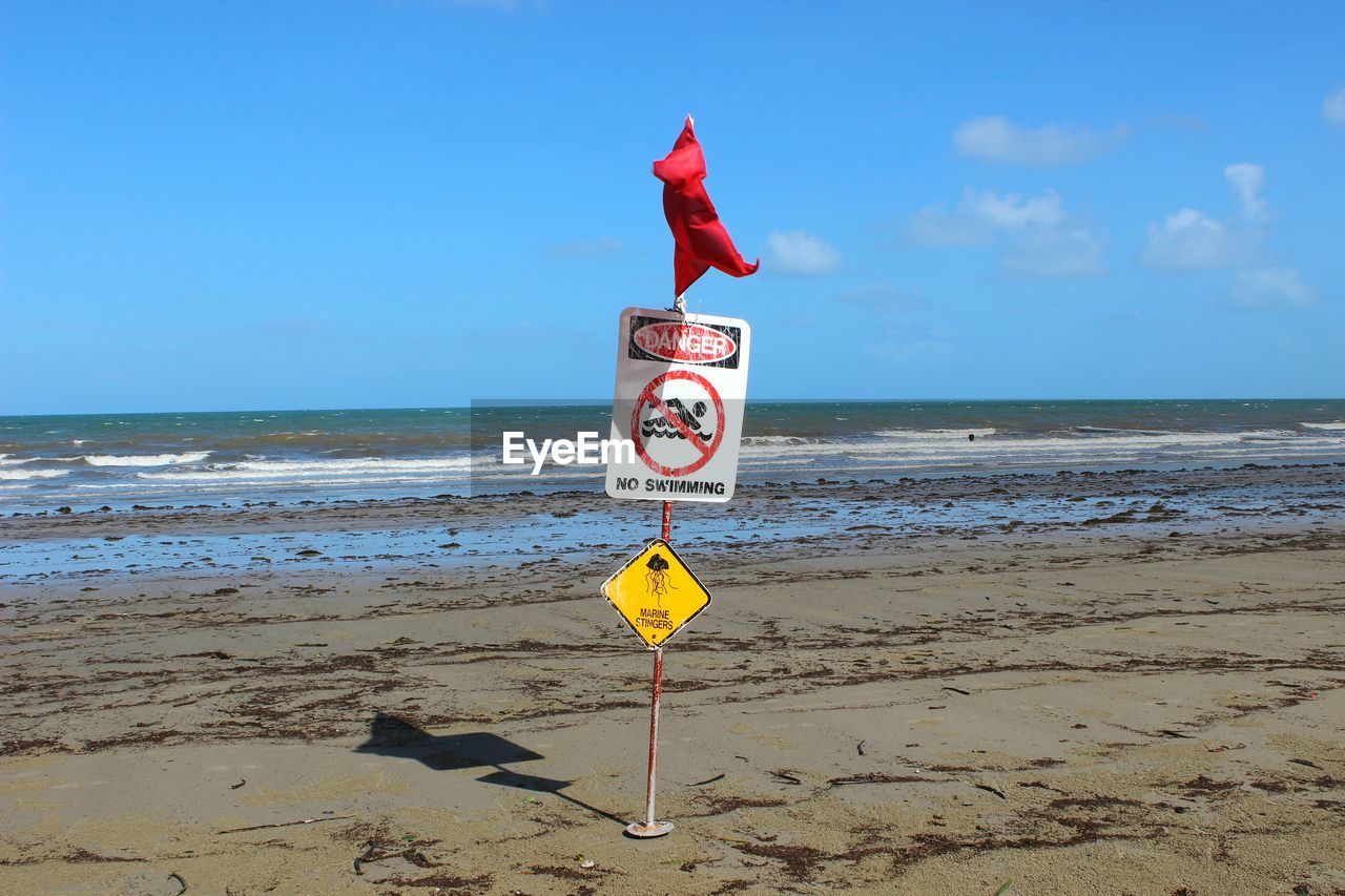 Information sign on beach against clear sky