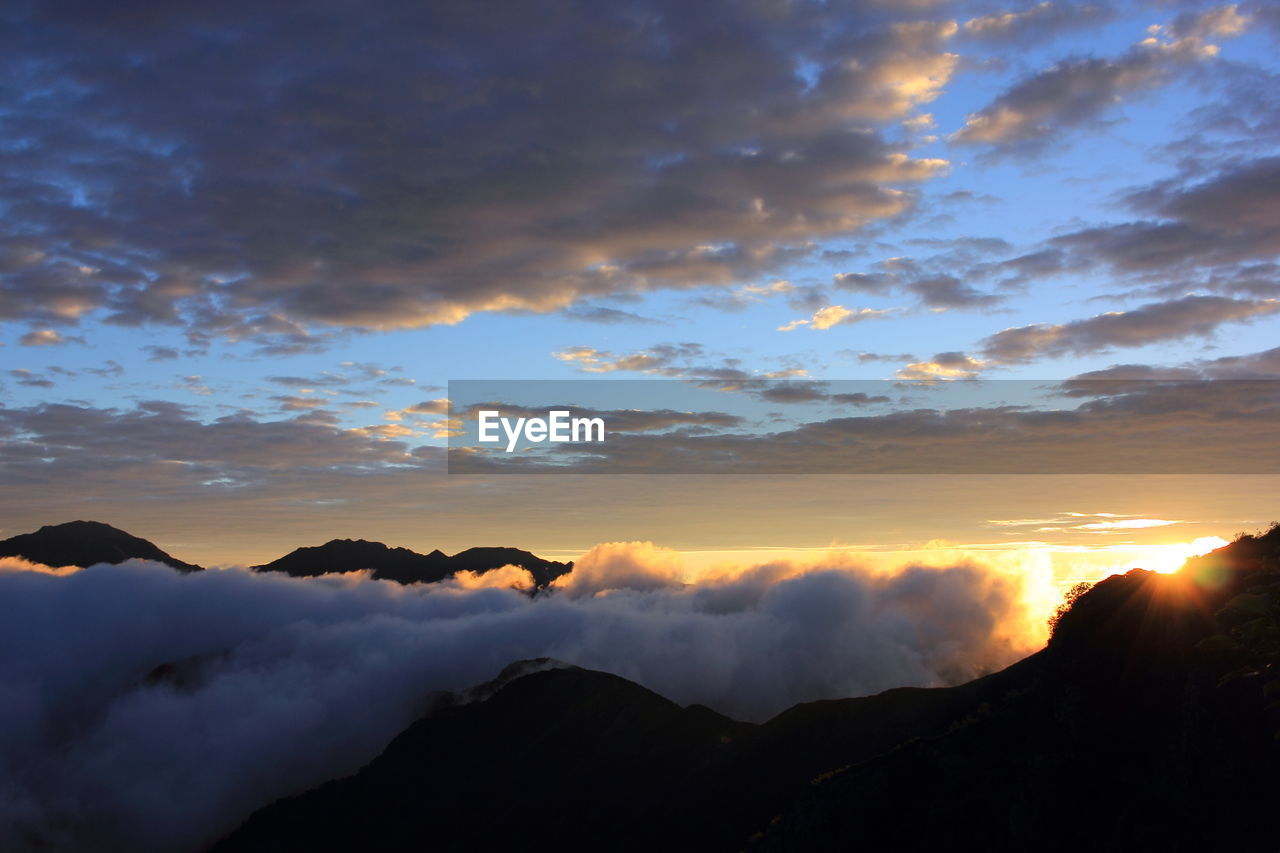 Scenic view of mountains against cloudy sky during foggy weather