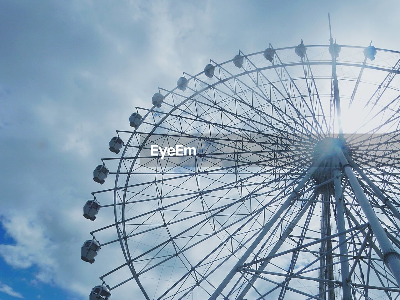 Low angle view of ferris wheel against cloudy sky
