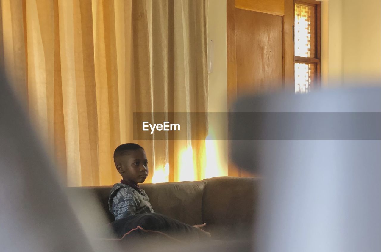 4 year old african boy, on couch, watching tv at home 
