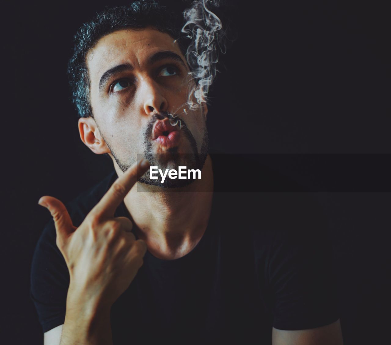 PORTRAIT OF MAN SMOKING OVER BLACK BACKGROUND