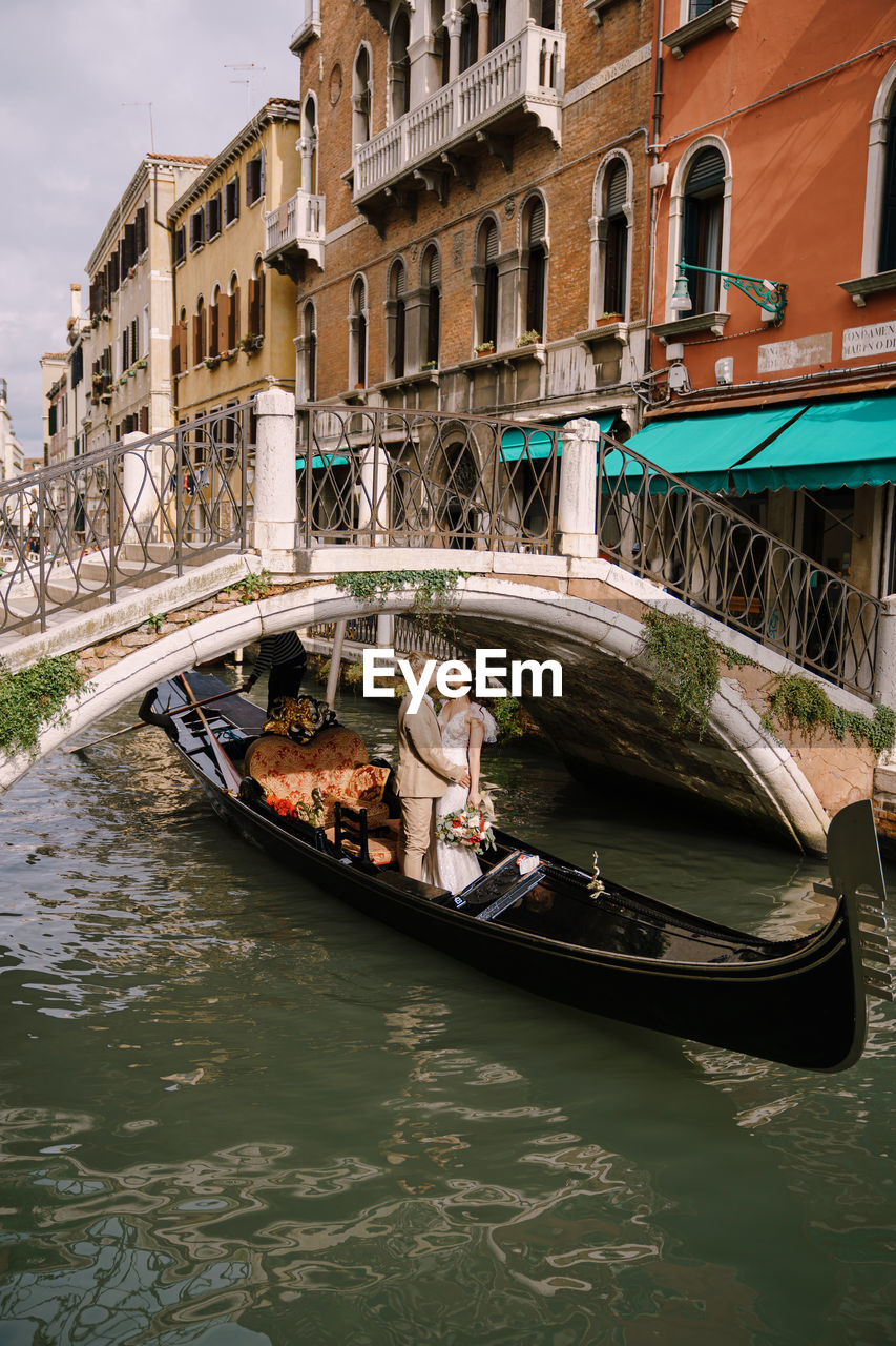 Couple standing in gondola at canal