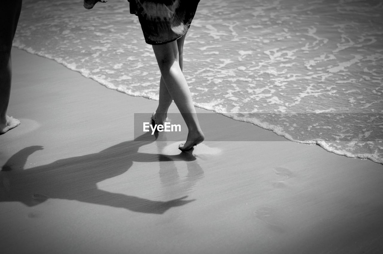 Low section of woman walking on sea shore