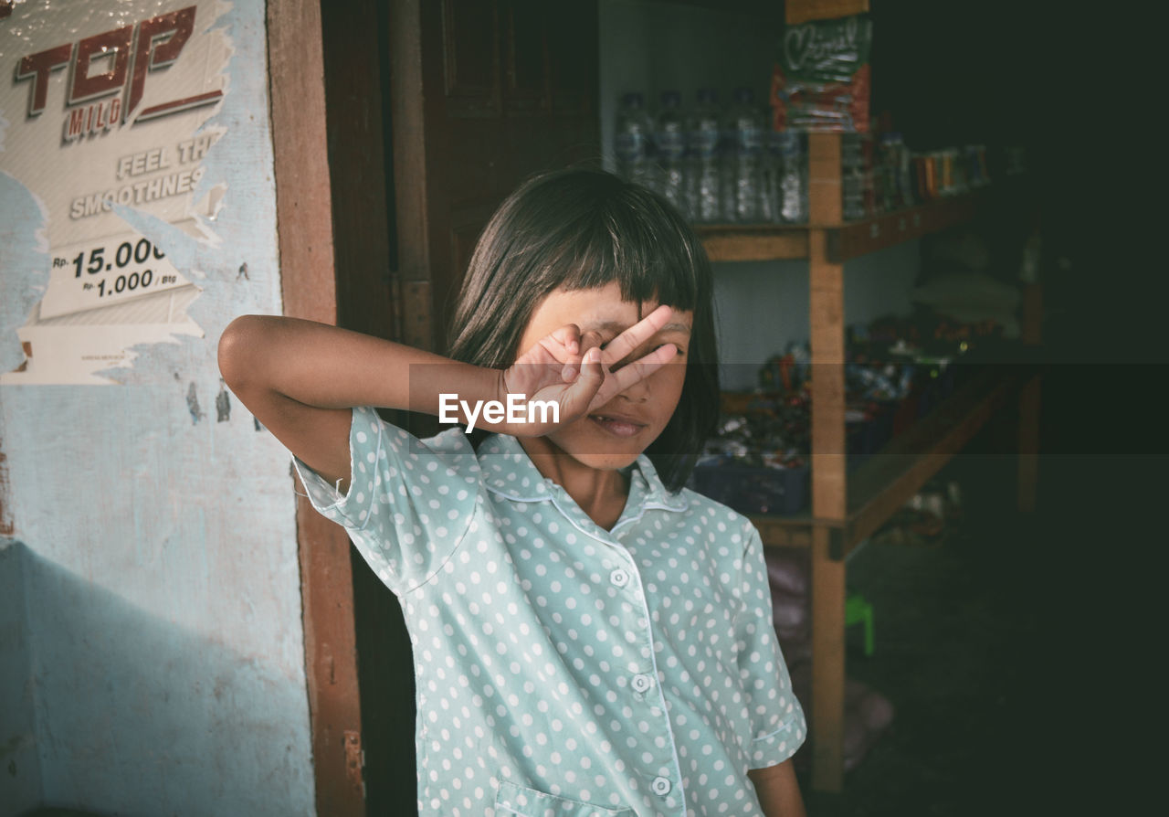 Portrait of woman standing by covering face