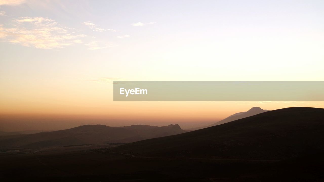 SCENIC VIEW OF MOUNTAINS AGAINST SUNSET SKY