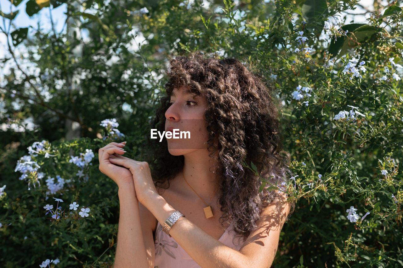 Woman with curly hair standing against sky