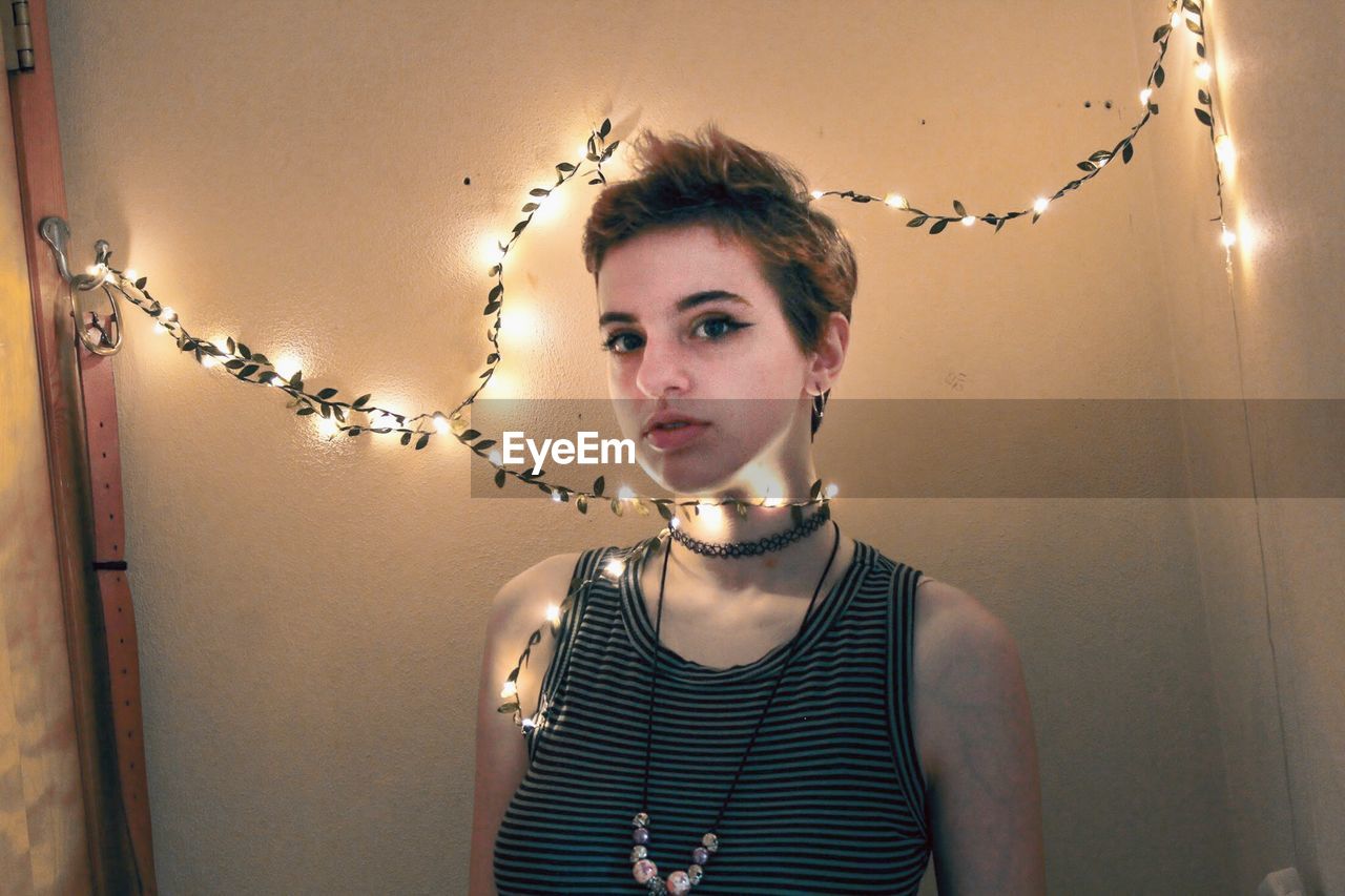 Portrait of woman with illuminated string lights at home