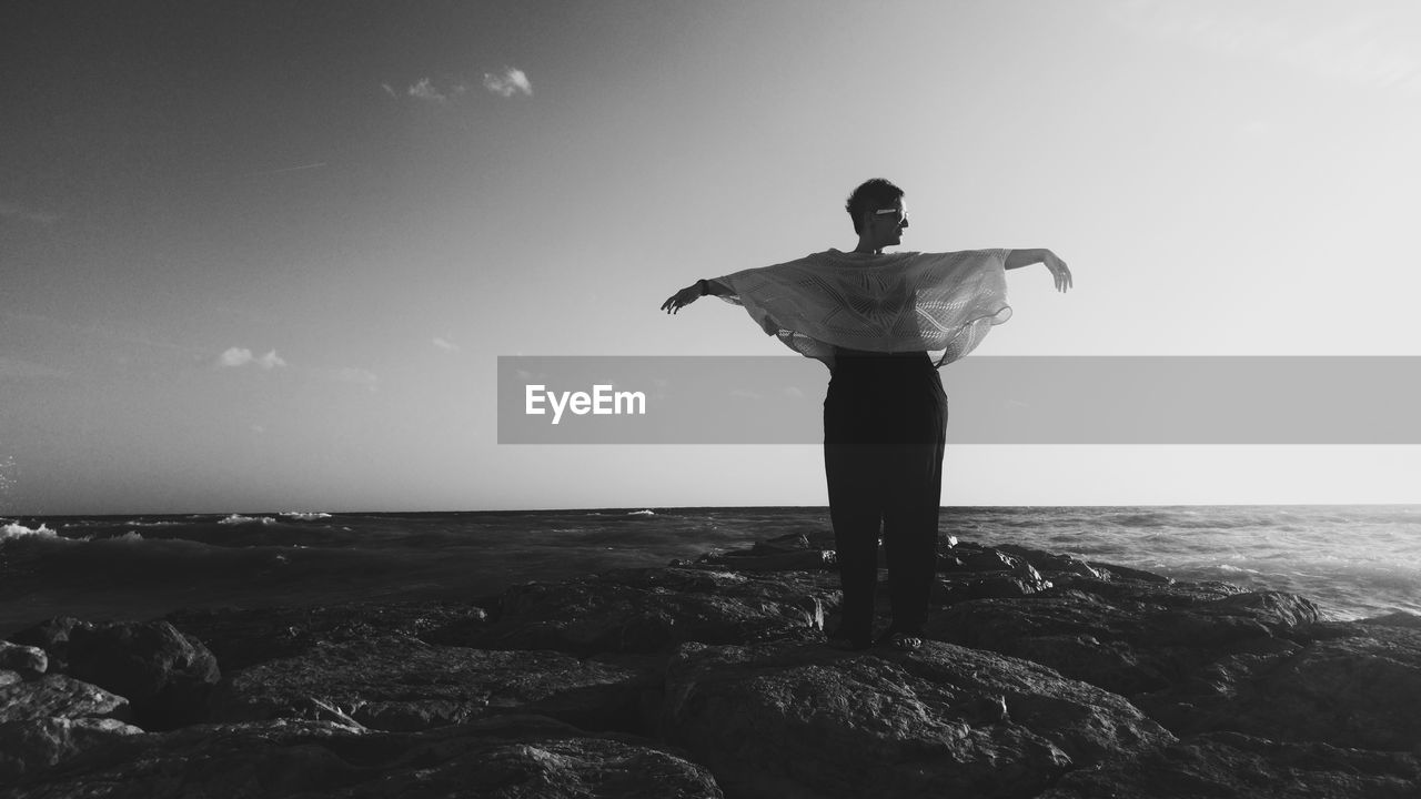 Full length of woman standing at beach against sky