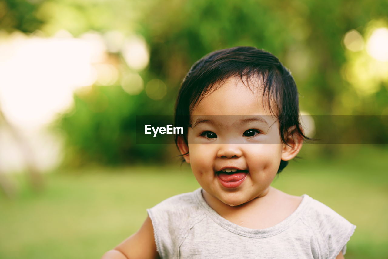 Close-up portrait of cute smiling baby girl standing at park