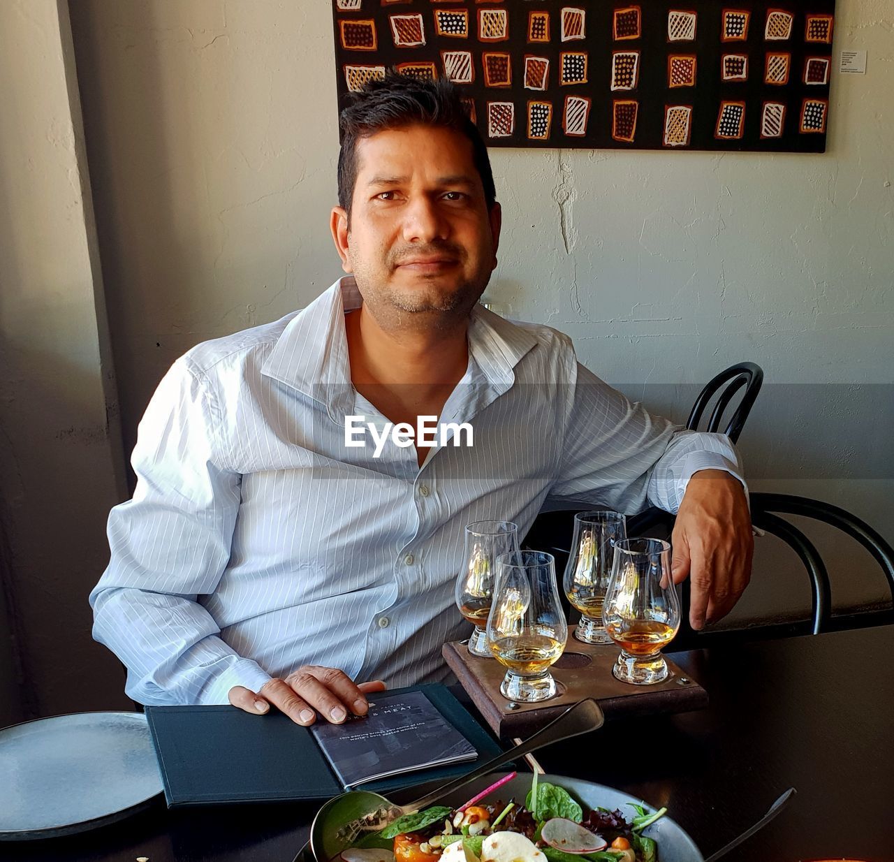 PORTRAIT OF YOUNG MAN SITTING AT RESTAURANT