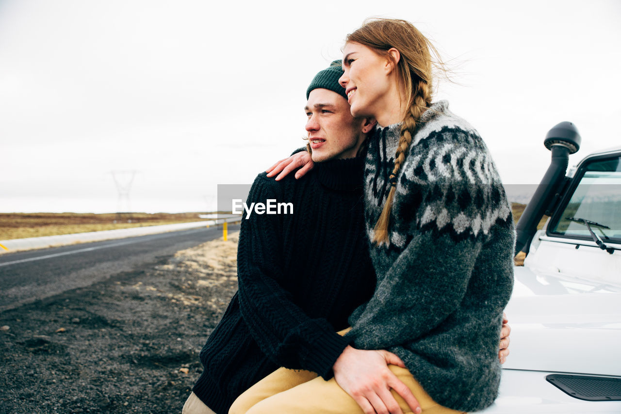 YOUNG COUPLE KISSING AGAINST CARS