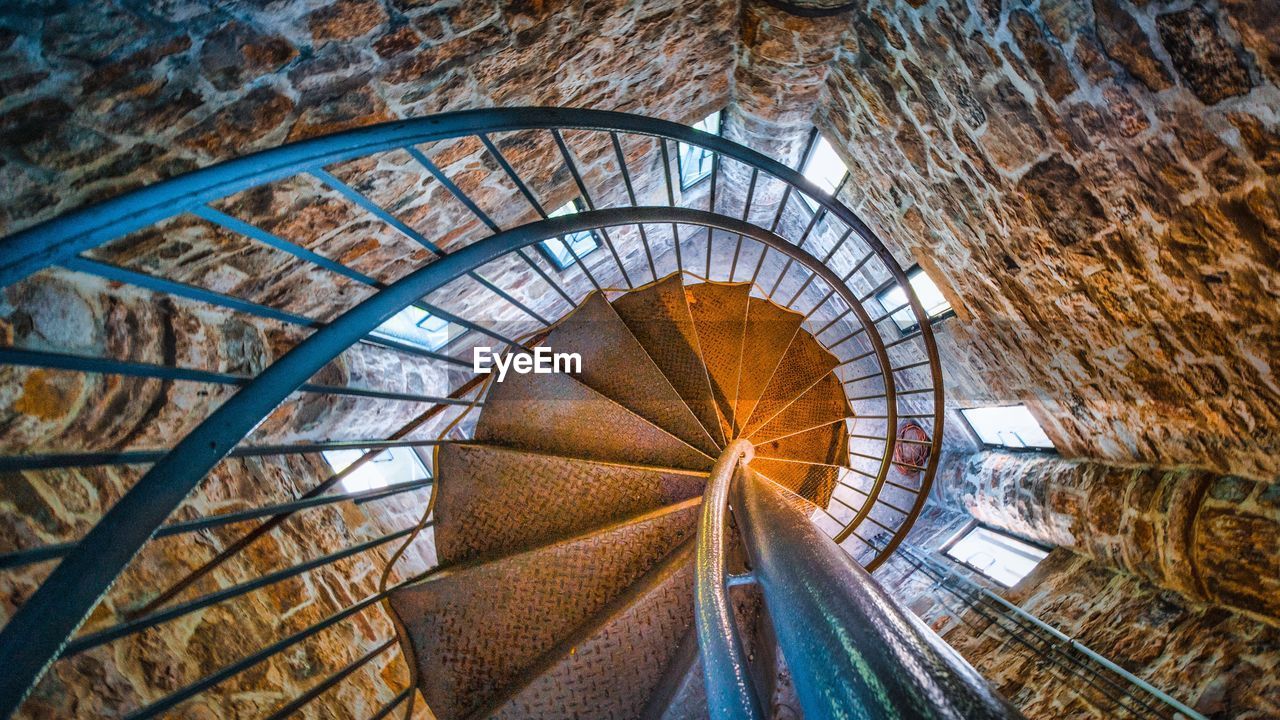 LOW ANGLE VIEW OF ILLUMINATED SPIRAL STAIRCASE