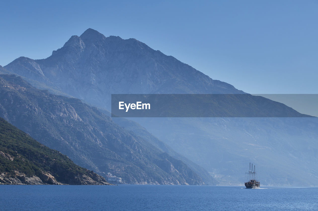 Cruise ship near the holy mountain - agion oros, athos, the summit and monasteries behind, greece