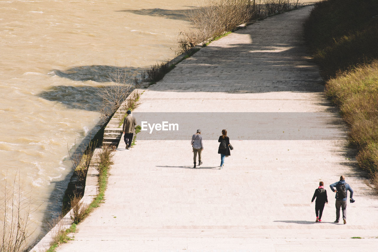 High angle view of people walking on footpath by river