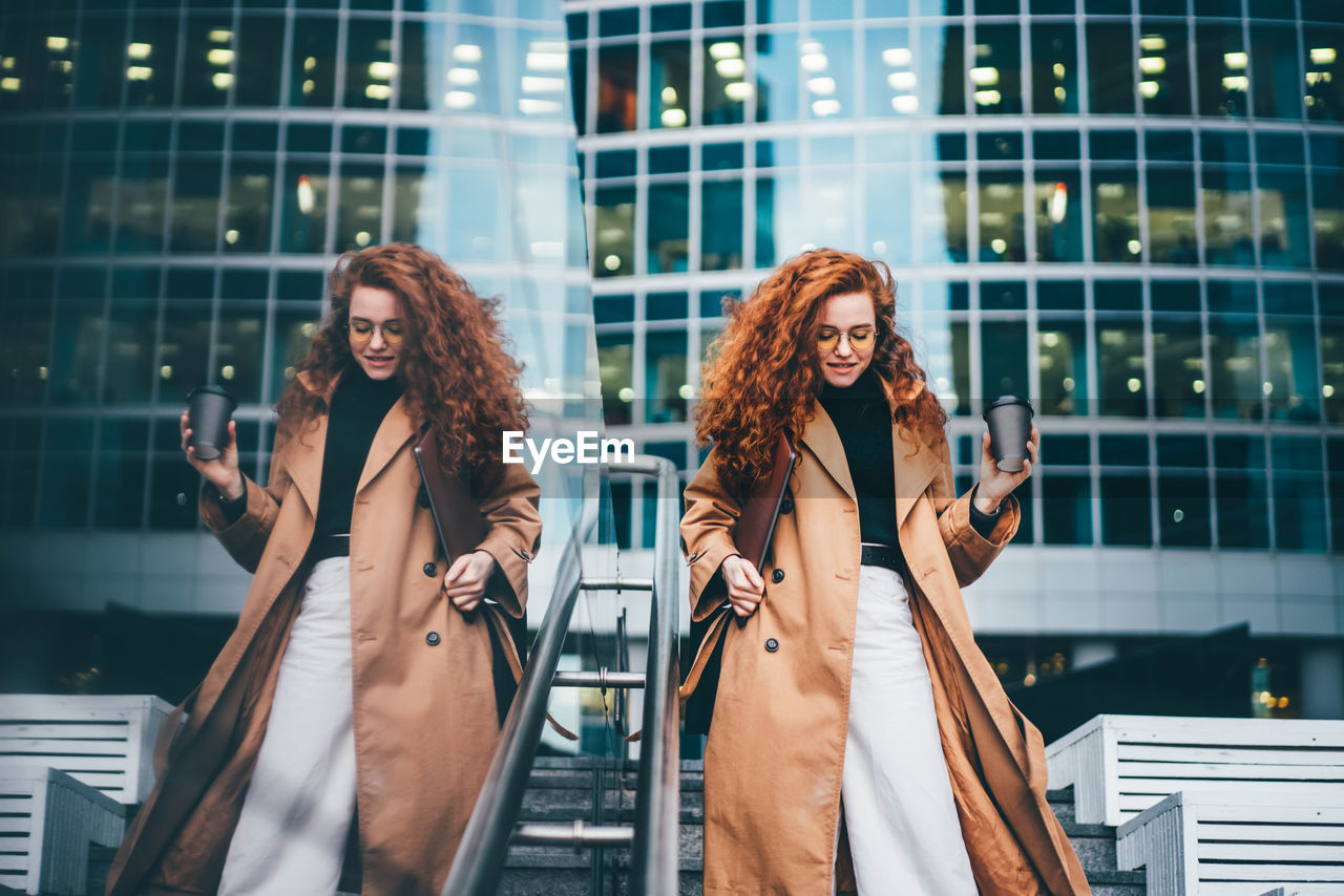 portrait of young woman standing against buildings in city