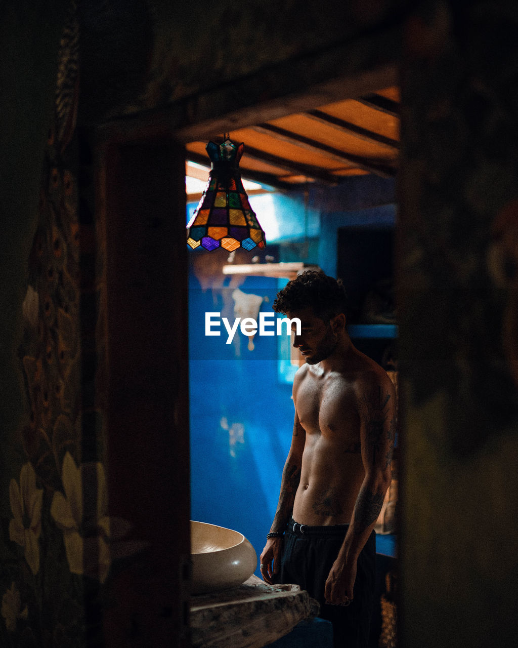 Rear view of shirtless man standing at home