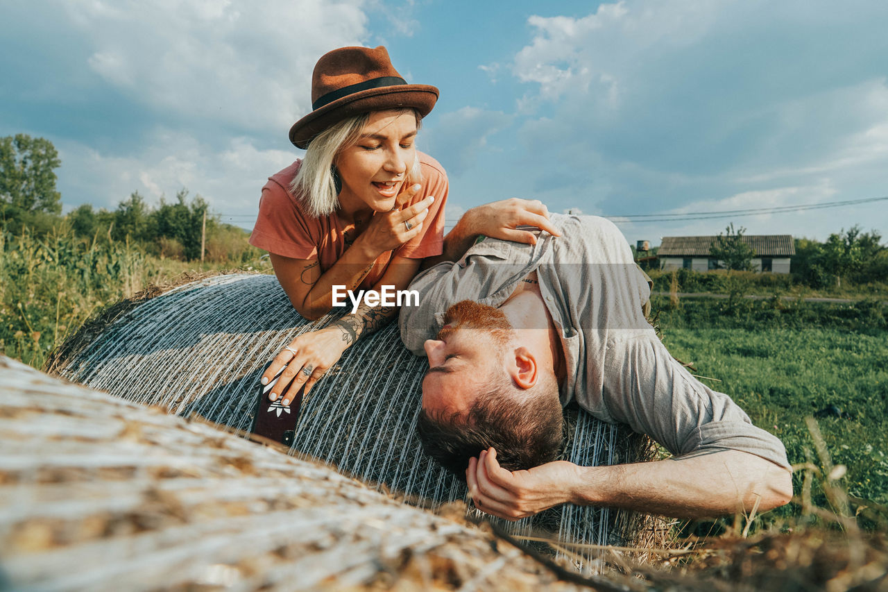 Smiling couple relaxing on hay bales