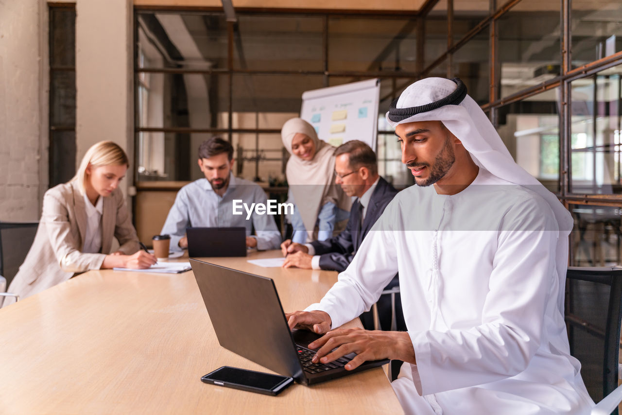 portrait of young woman using laptop while standing in office