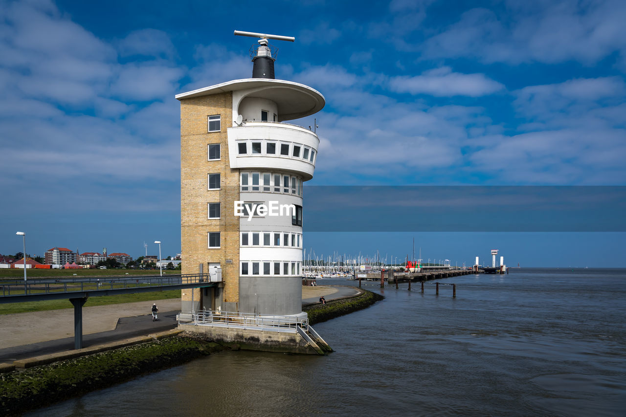 Lighthouse on building by sea against sky