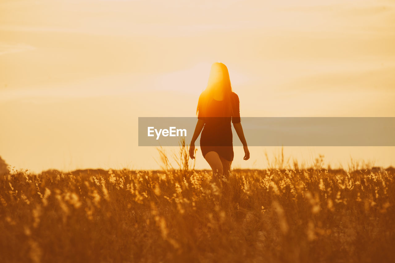 Beautiful women walking through field against clear sky