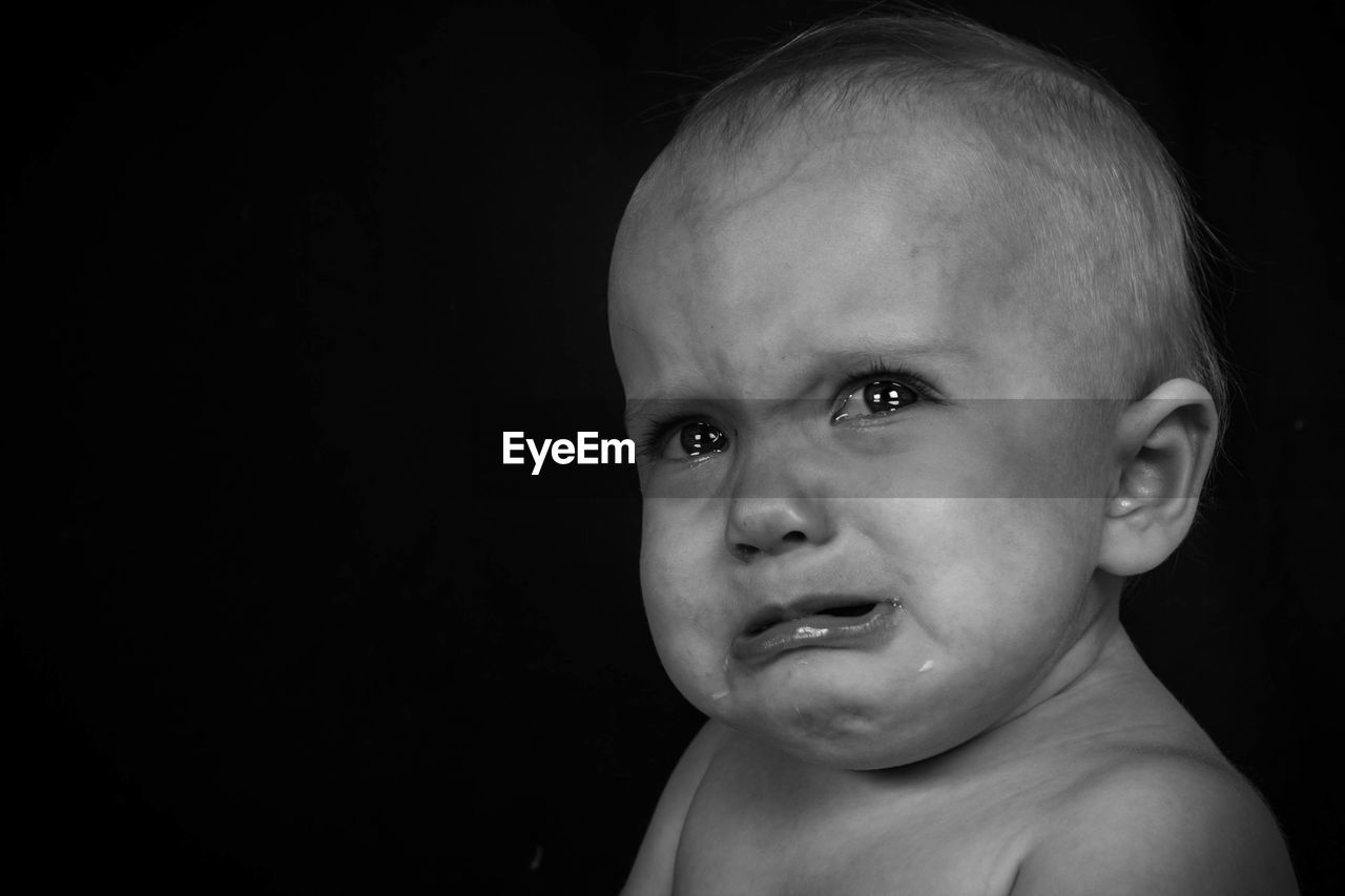 Close-up of crying baby girl against wall