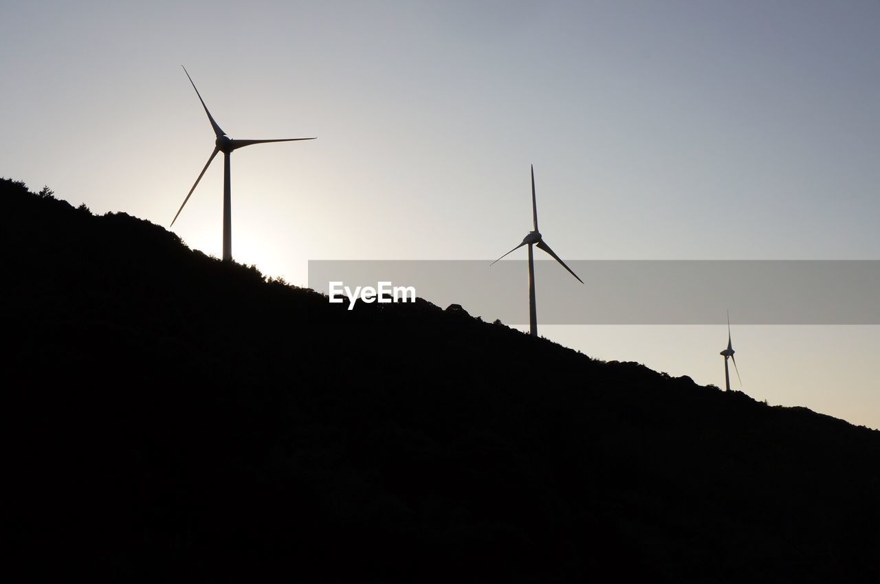 LOW ANGLE VIEW OF SILHOUETTE WIND TURBINES AGAINST SKY