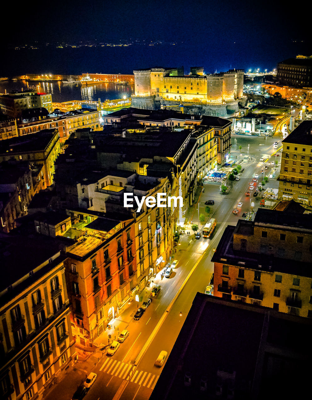 High angle view of illuminated street amidst buildings in city at night