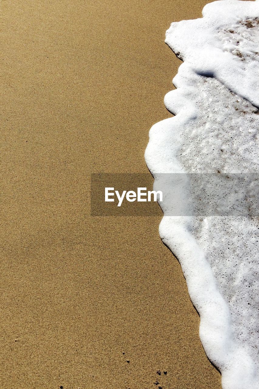 High angle view of surf at beach on sunny day