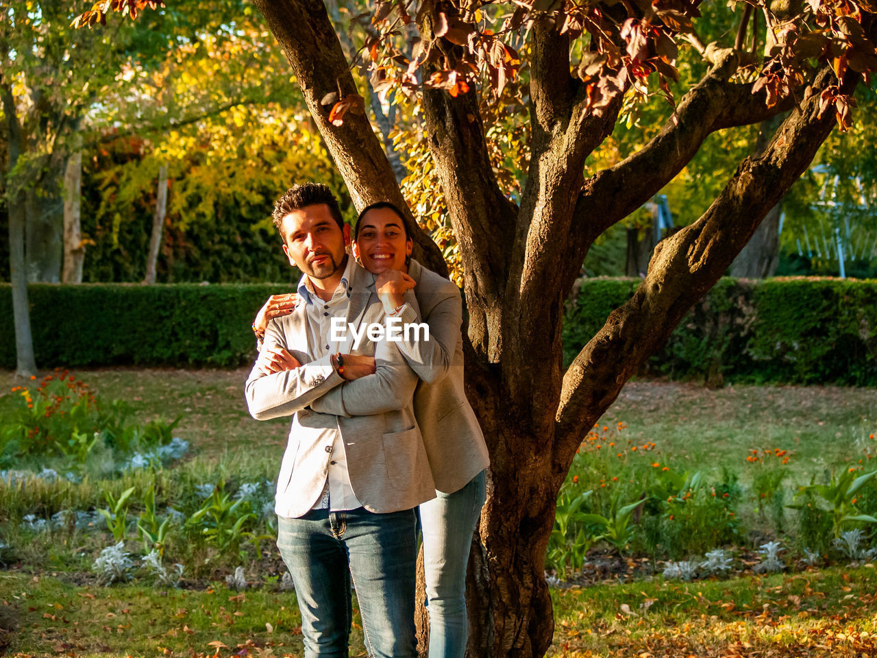 Portrait of smiling couple standing against trees in park