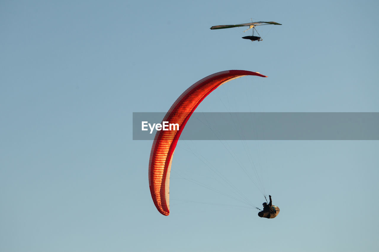 LOW ANGLE VIEW OF PEOPLE PARAGLIDING