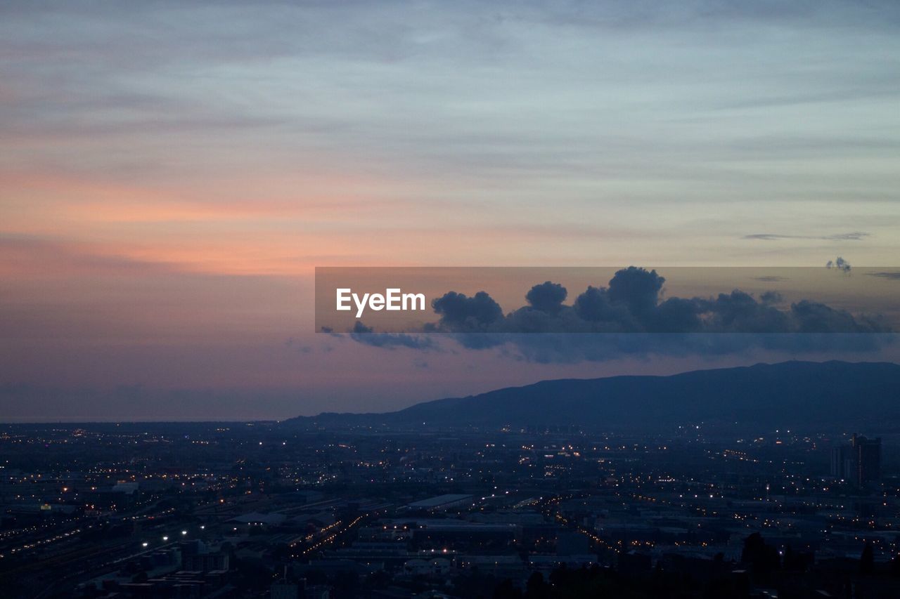 Aerial view of illuminated city against sky at sunset