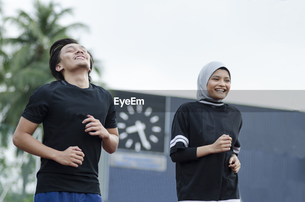 Young happy couple enjoying in a healthy lifestyle, warming up and stretching before jogging