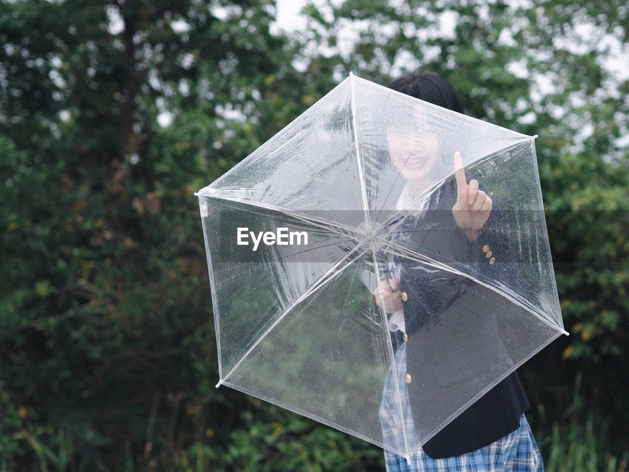 Young woman holding transparent umbrella at park